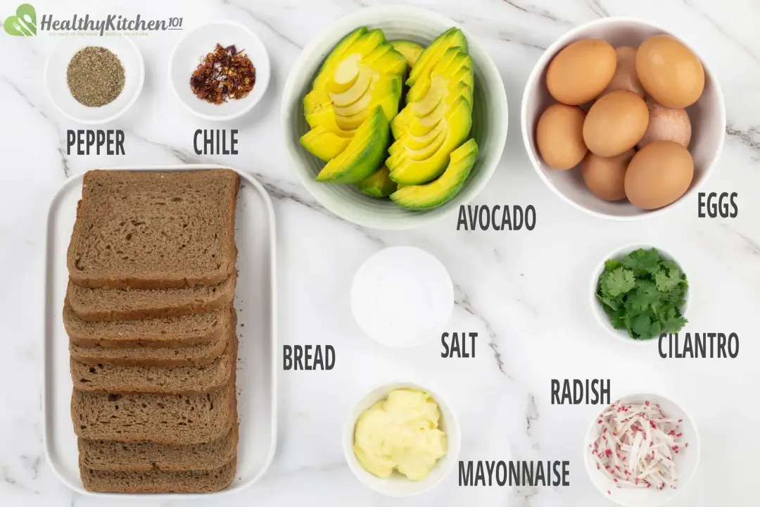 Ingredients for avocado toasts: brown bread slices, whole eggs, cut-up avocados, herbs and seasonings