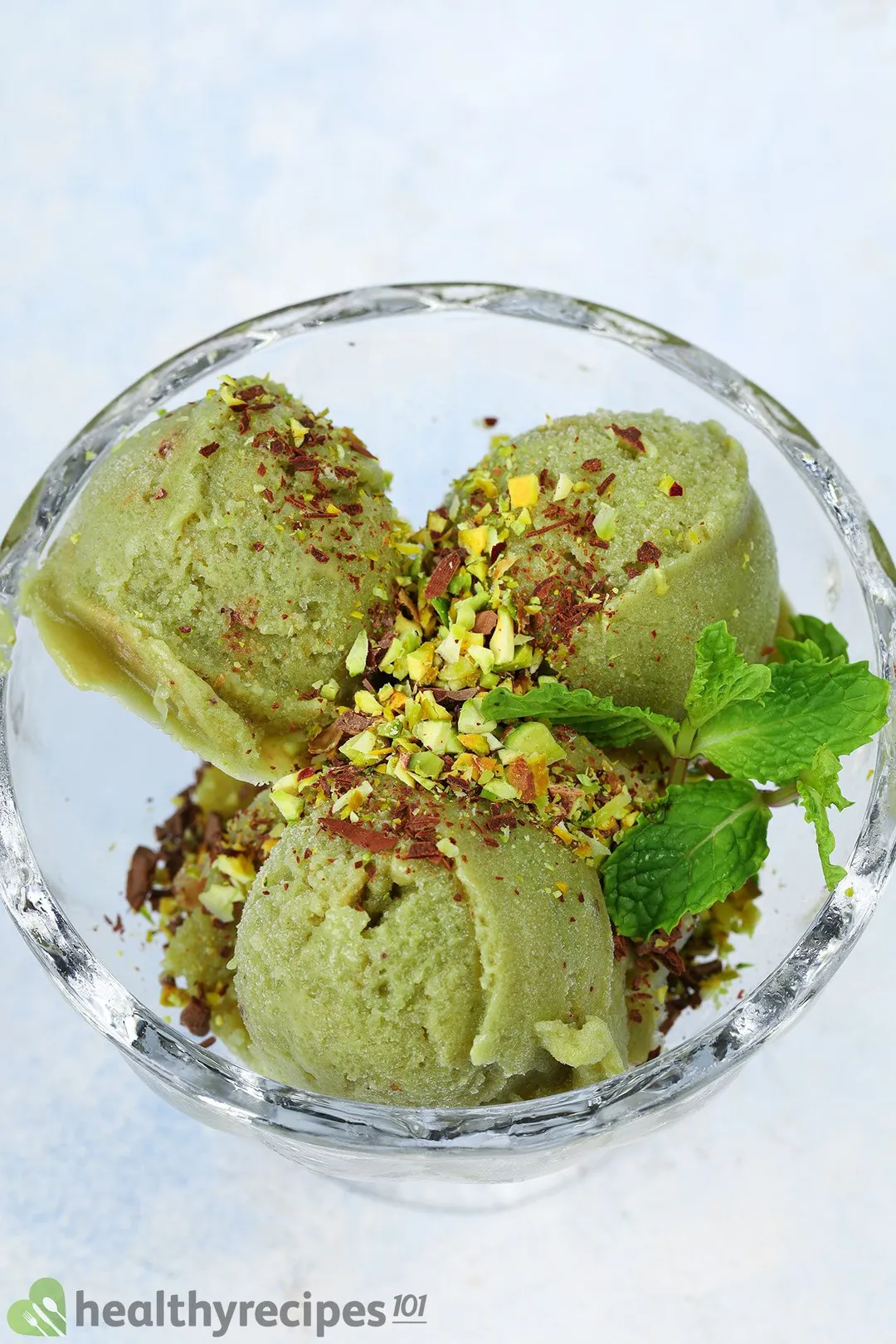 a glass bowl of avocado ice cream garnished by mint leaves