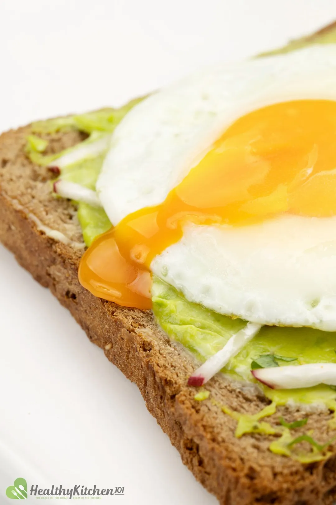 an sunny side up egg on toast with mashed avocado