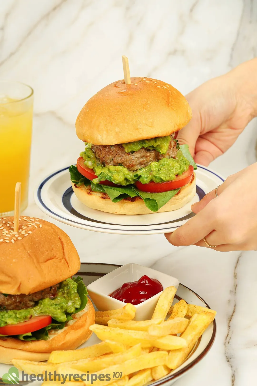 two hand holding a plate of burger on top of a plate with burger and french fries