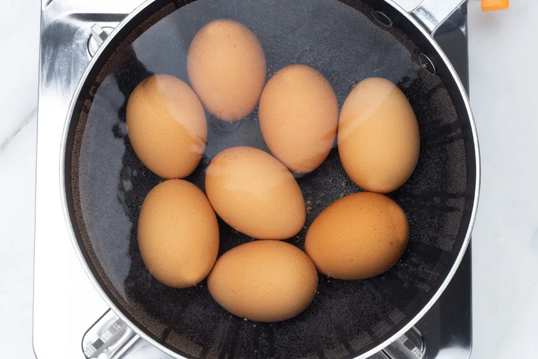 eight eggs boiling in a pot