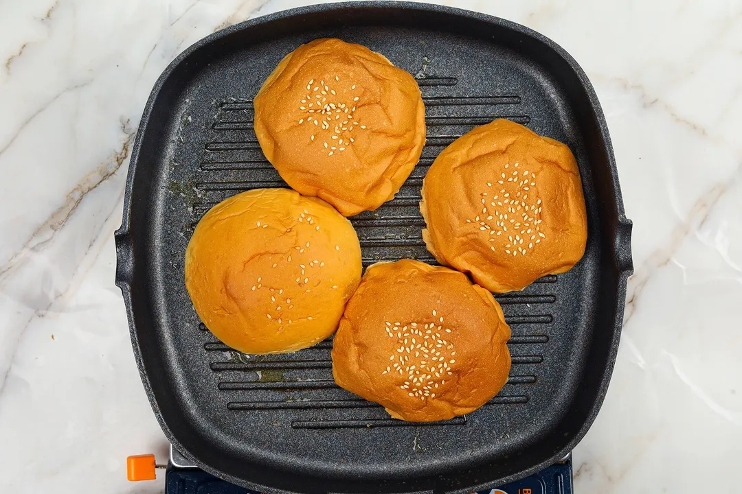 four half hamburger buns on a grill pan