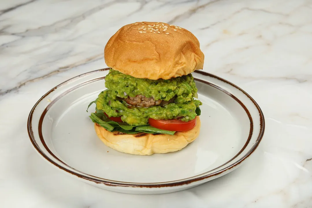 front shot of a hamburger with mashed avocado and patty inside