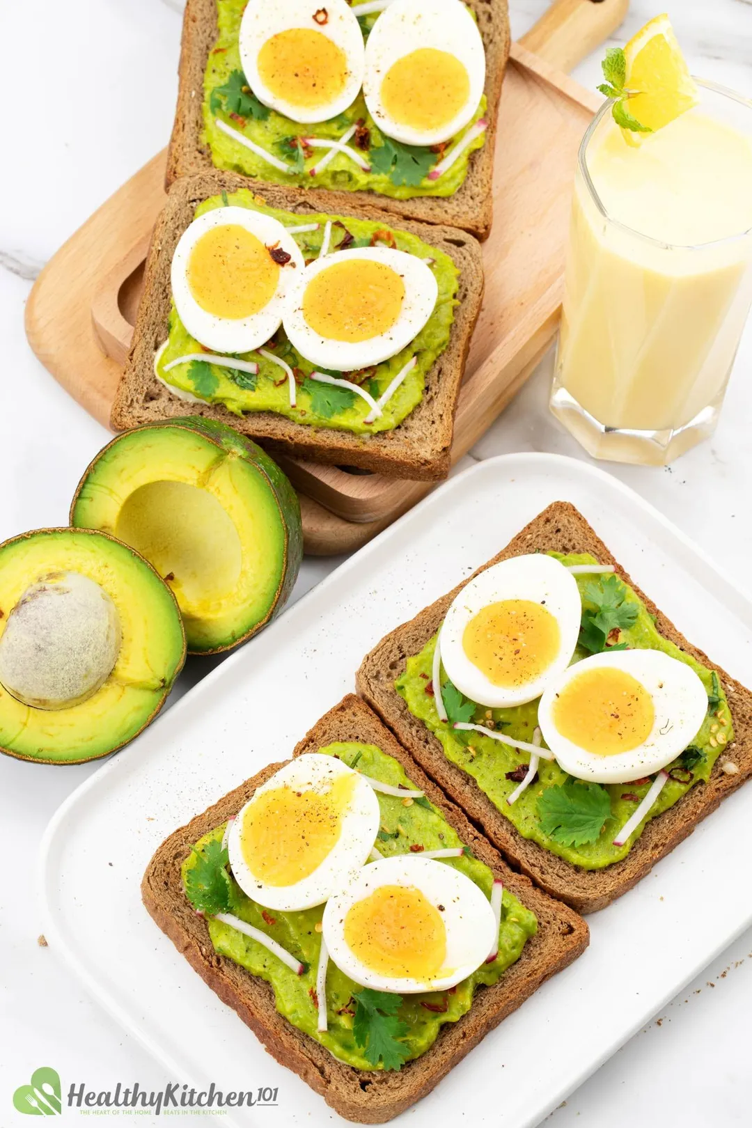 some half of boiled eggs on toasts with mashed avocado on them decorated by two half of avocado