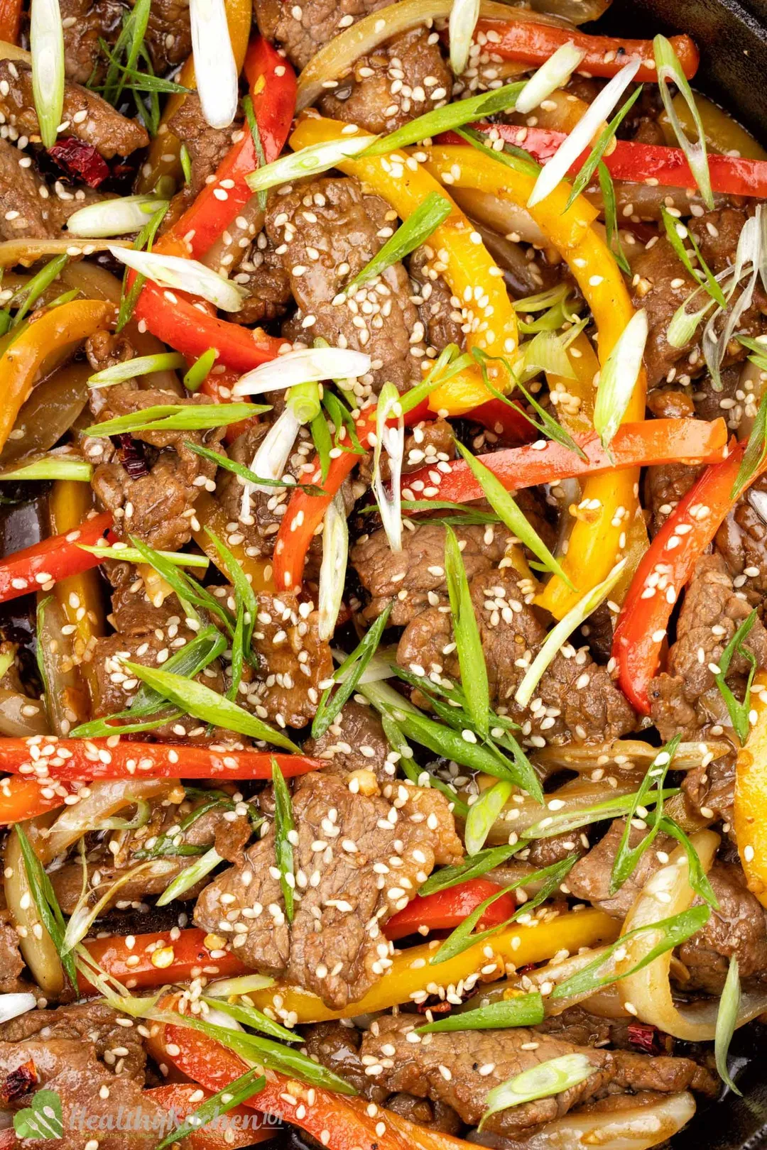 close-up shot of cooked beef with sliced bell pepper, chopped scallion and sesame seeds 
