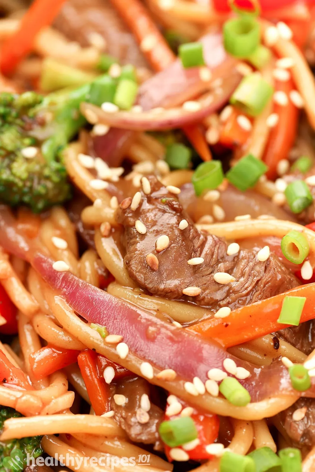 close-up shot of cooked beef and veggies, decorated with chopped scallion and sesame seeds