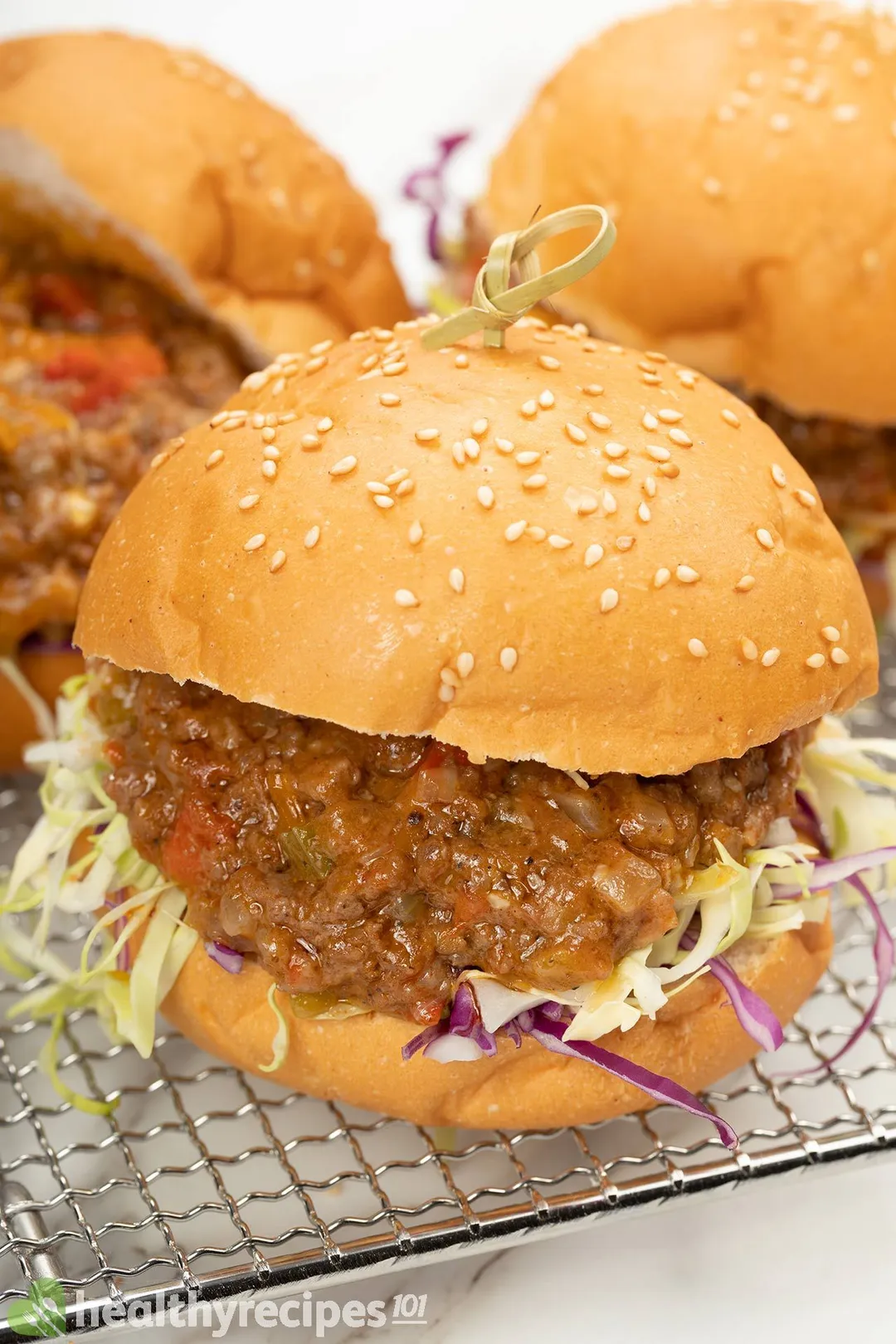 three burger with cooked ground beef and shredded cabbage in side