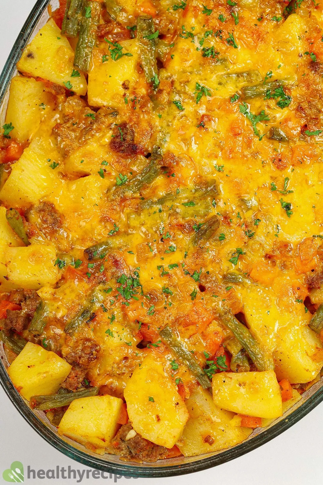 a casserole of cooked beef with cubed potatoes, green bean and cheddar cheese