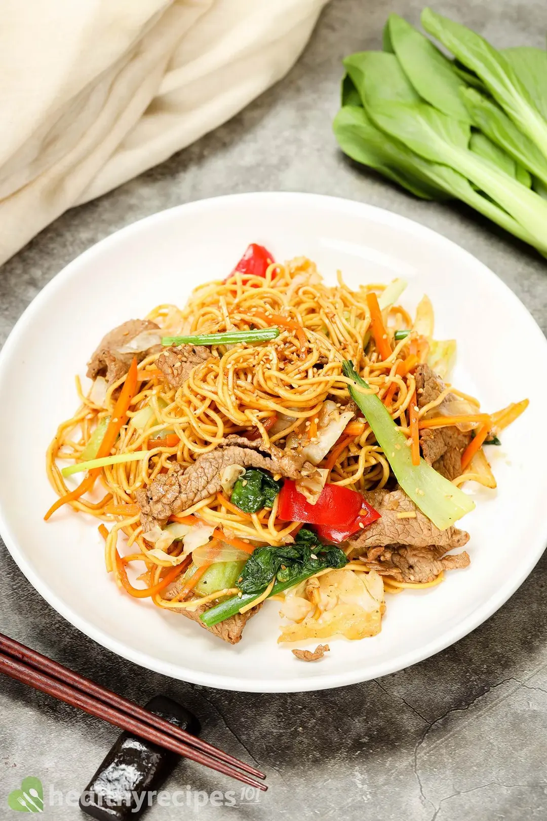 a plate of beef and noodle with vegetable and sesame seeds