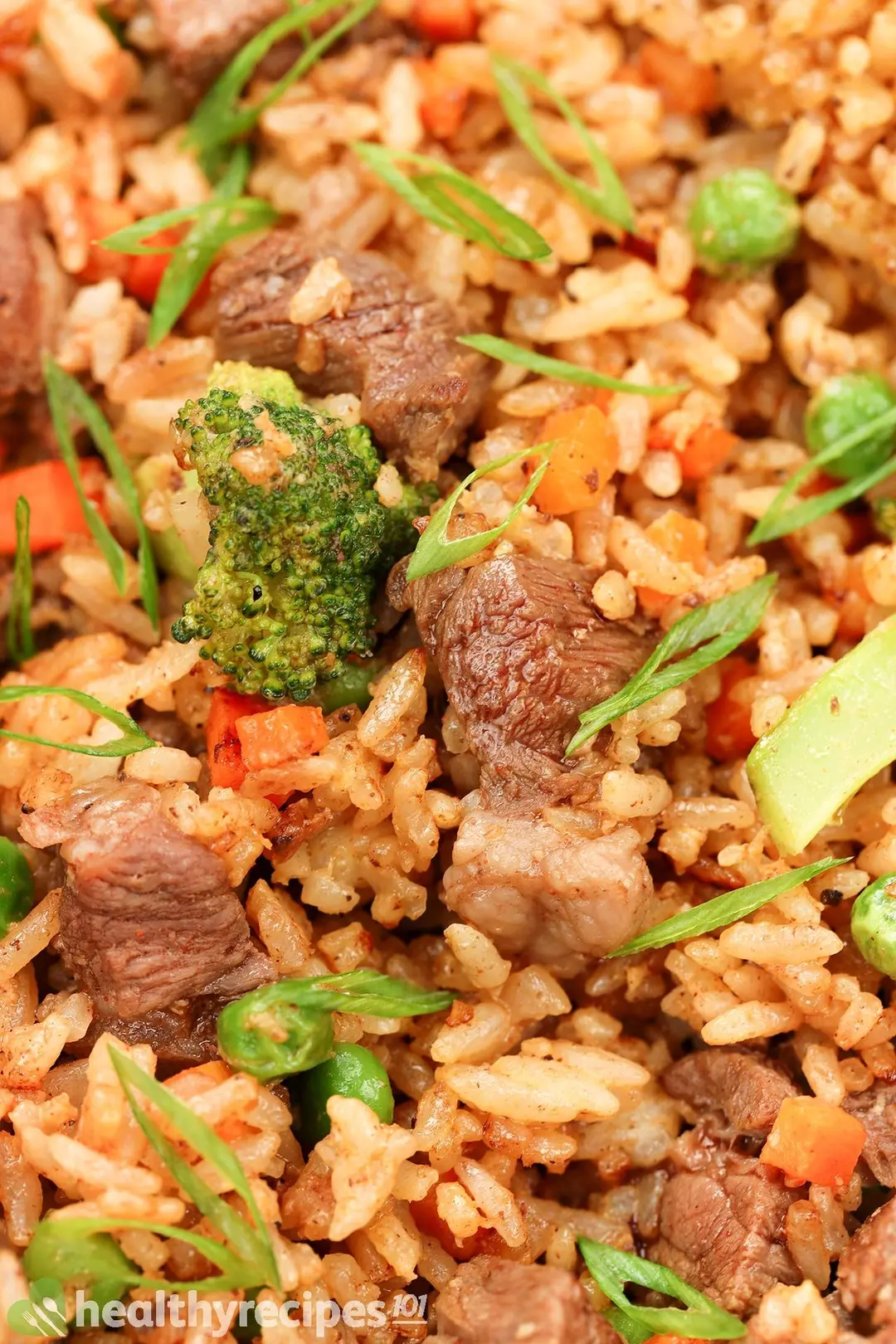 close-up shot of cooked beef cubed with rice and broccoli, garnished by carrot cubed and chopped scallion