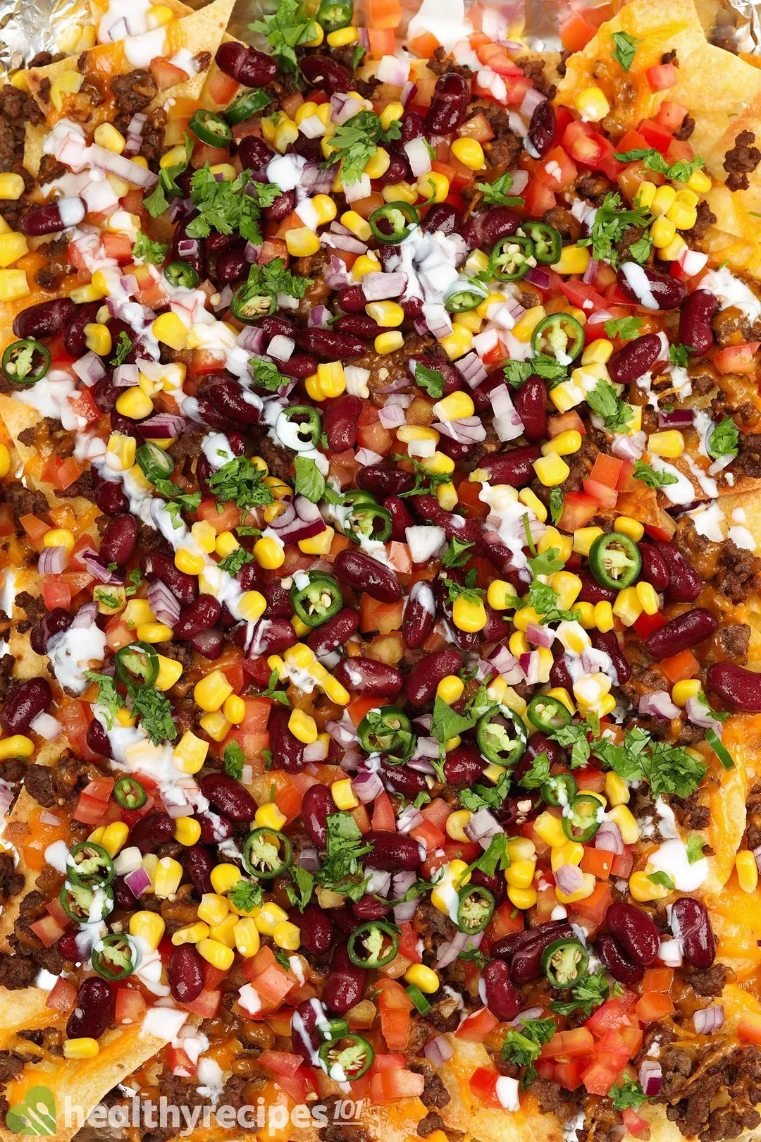 close-up view of cooked ground beef, red bean, corn, jalapeño sliced, tomatoes diced and chopped coriander