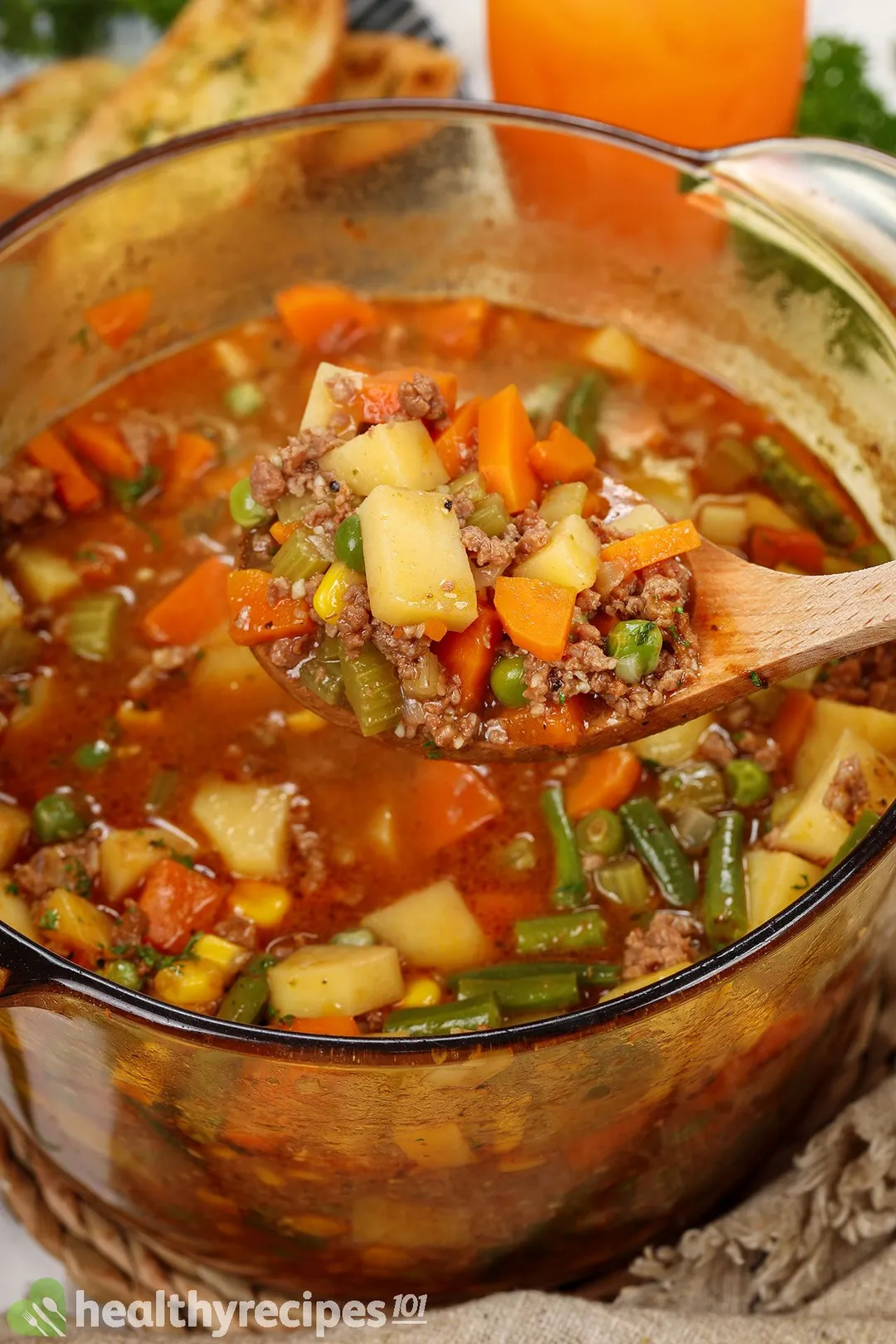 a wooden spoon full of topping on top of a pot of ground beef soup