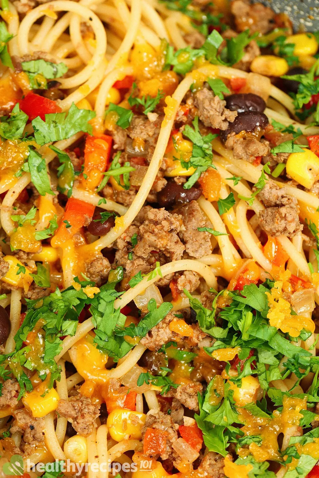 close-up shot of cooked spaghetti with ground beef and veggies, garnished with chopped coriander