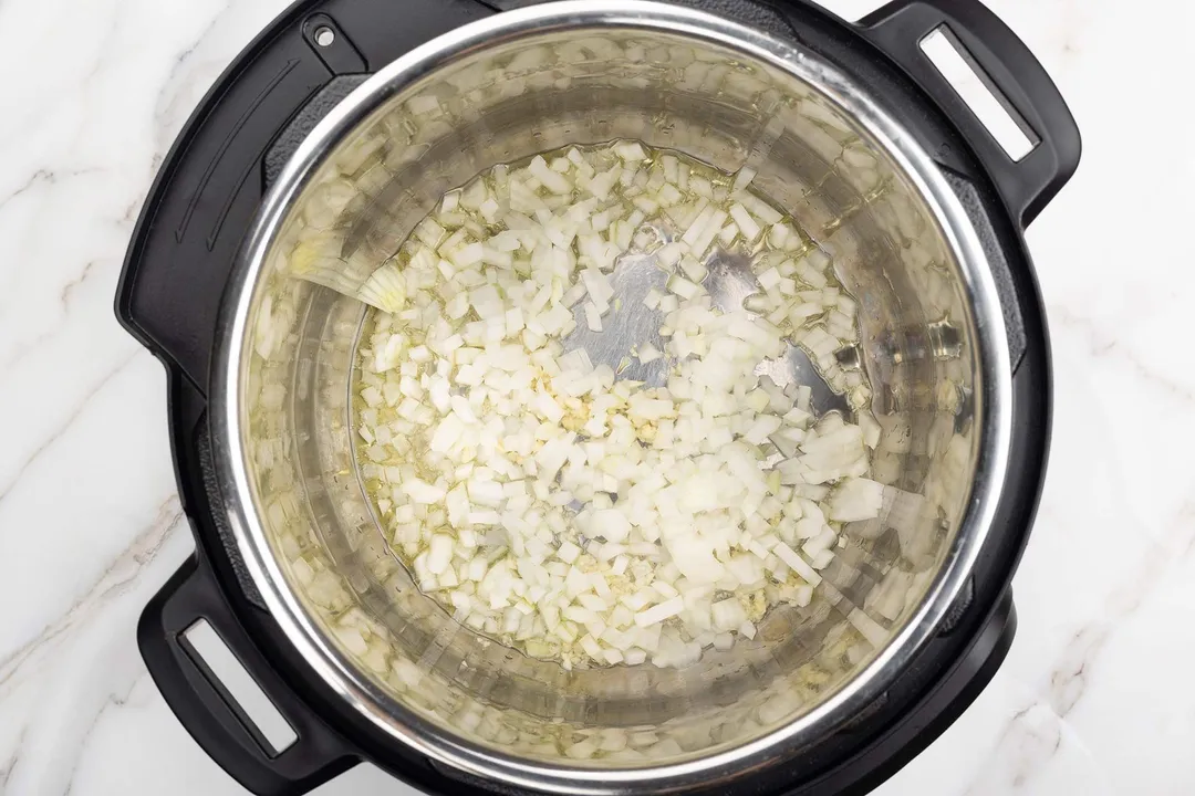 minced onion and minced garlic cooking in an instant pot