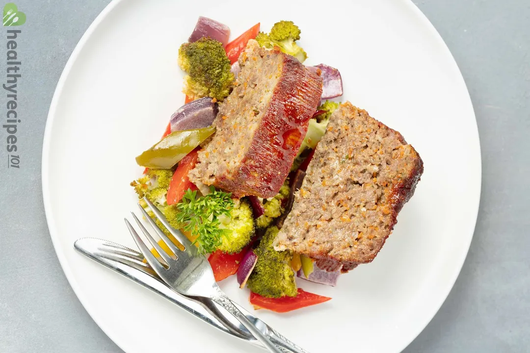cooked meatloaf on a plate with veggies