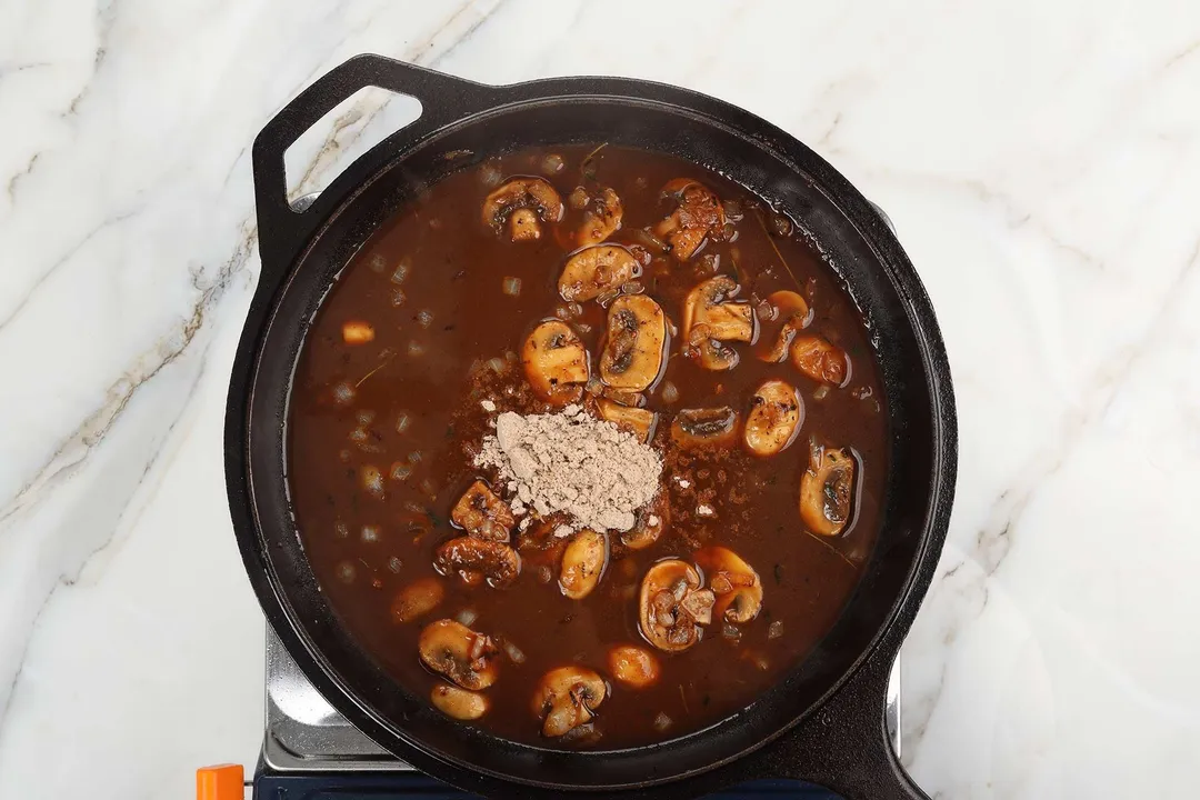 mushroom, sauce and gravy mix cooking in a cast iron skillet
