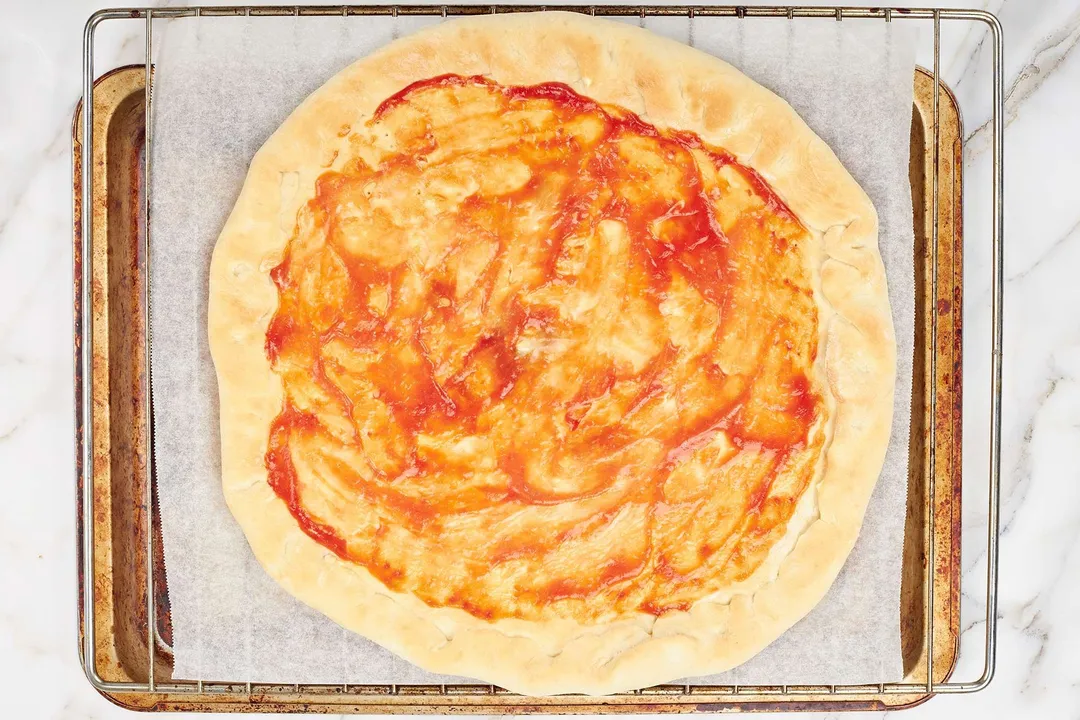 spread ketchup over the base on top pizza dough