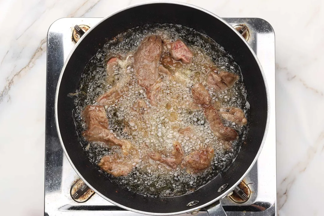 sliced beef frying in a non-stick skillet