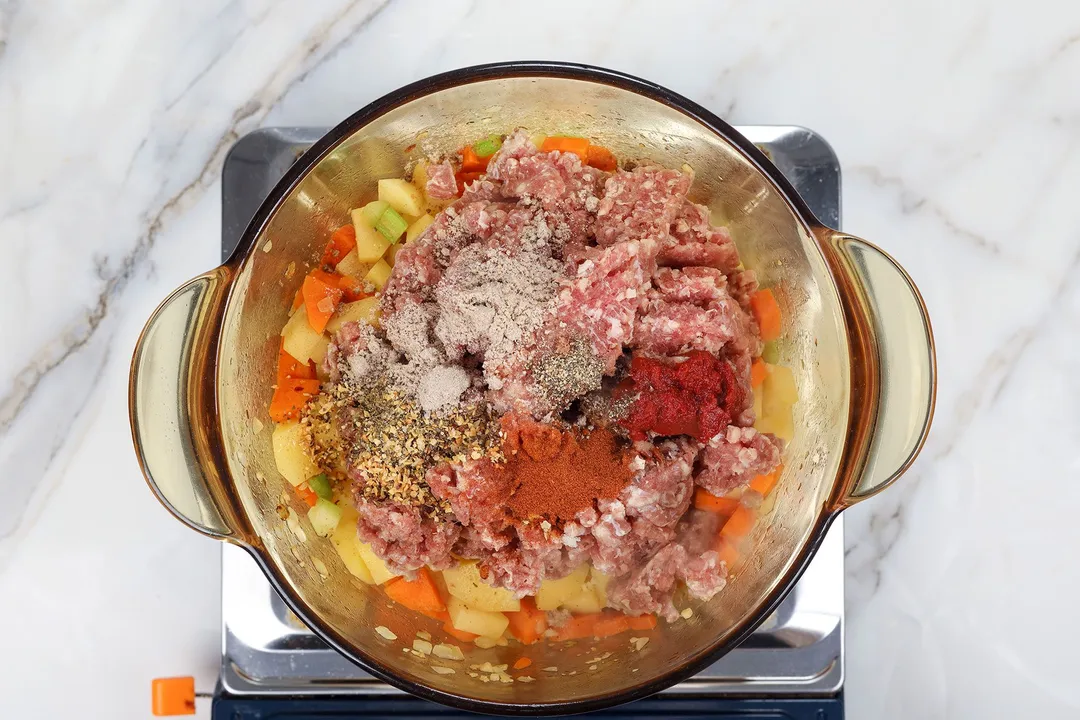 ground beef, seasoning and potato cubes, carrot cubes in a pot