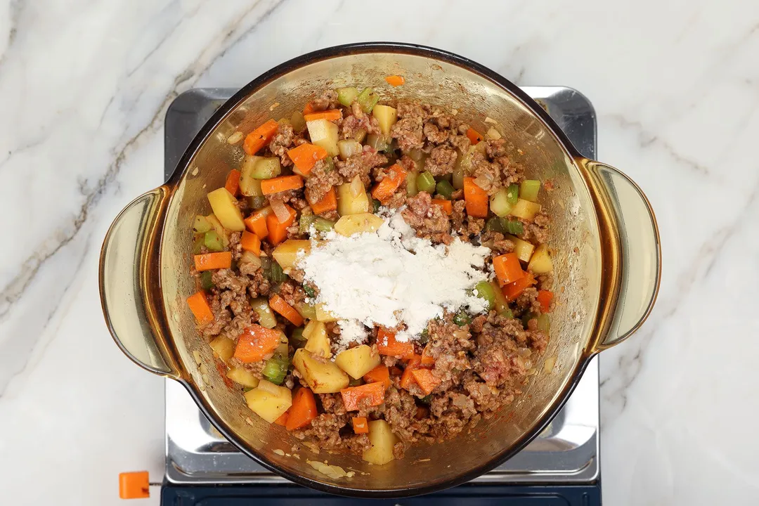 flour and cooked ground beef with vegetables in a pot