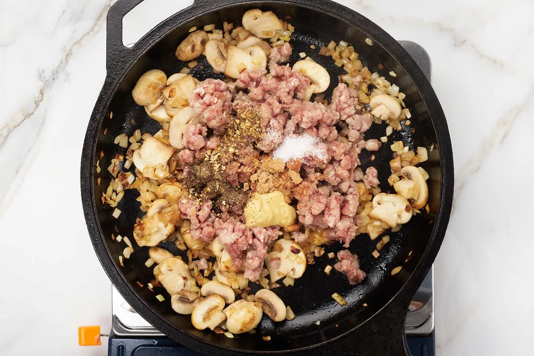 ground beef, spicy and mushroom cooking on a cast iron skillet