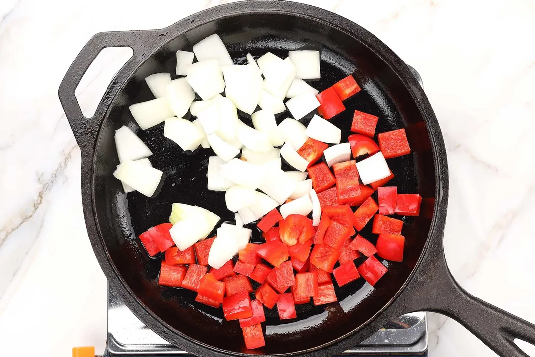 diced red pepper and diced onion on a cast iron skillet