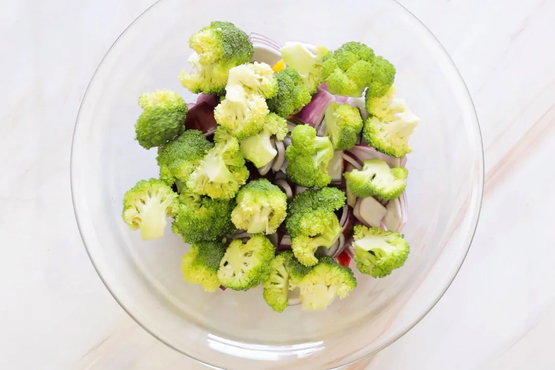 a glass bowl of broccoli florets, onion cubed 