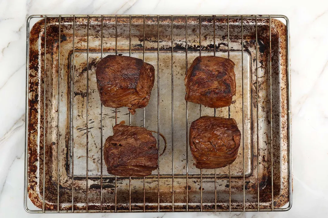 four cooked beef tenderloin on a wire rack on a baking sheet