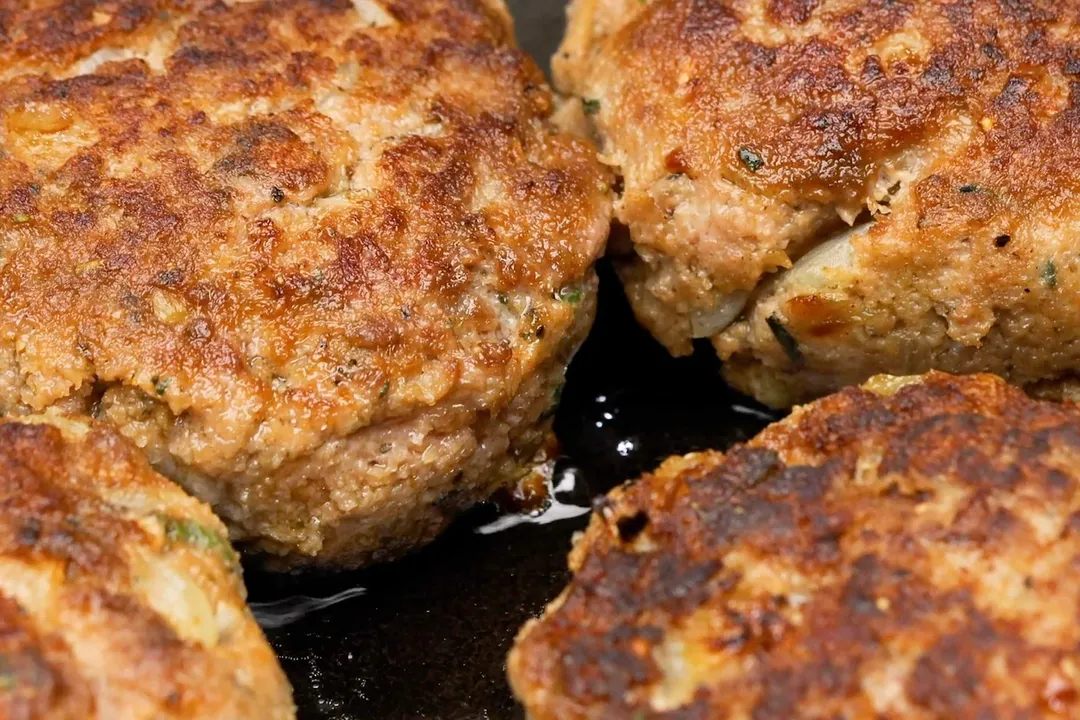 beef patties searing on a cast iron skillet