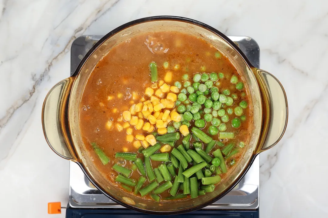 corn, peas and beans cooking in a pot of soup