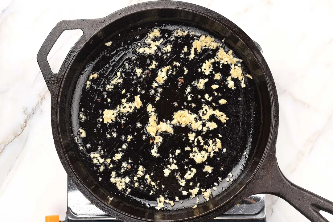 minced garlic cooking on a cast iron skillet