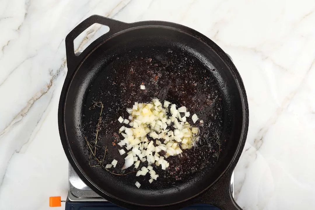 diced onion cooking in a cast iron skillet