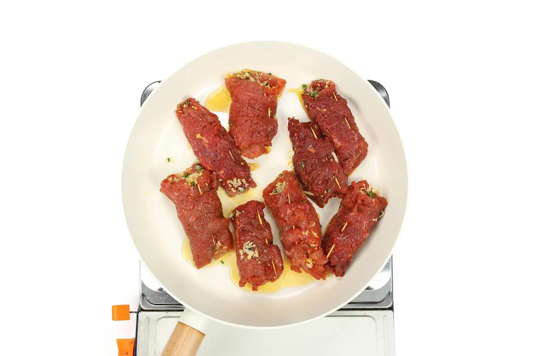 searing beef braciole in a skillet