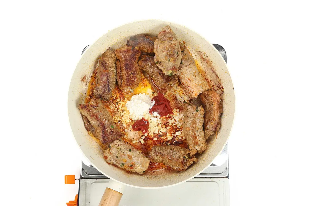 seared beef braciole and seasoning in a skillet
