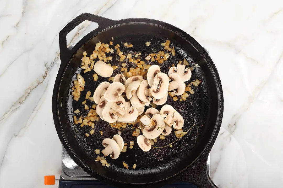 mushroom and diced onion cooking in a cast iron skillet