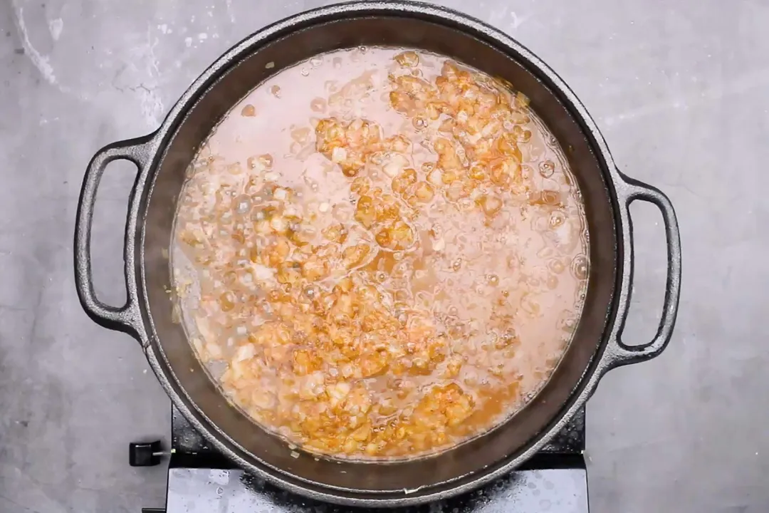 minced onion, tomato sauce and spicy, water cooking on a cast iron skillet