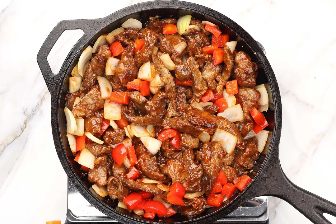 diced onion and pepper cooking with beef on a cast iron skillet