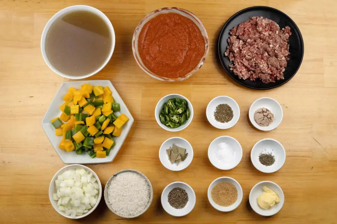 Ingredients for stuffed pepper soup in separate bowls: green and yellow peppers cut into chunks, minced beef, sauce, broth, and seasonings
