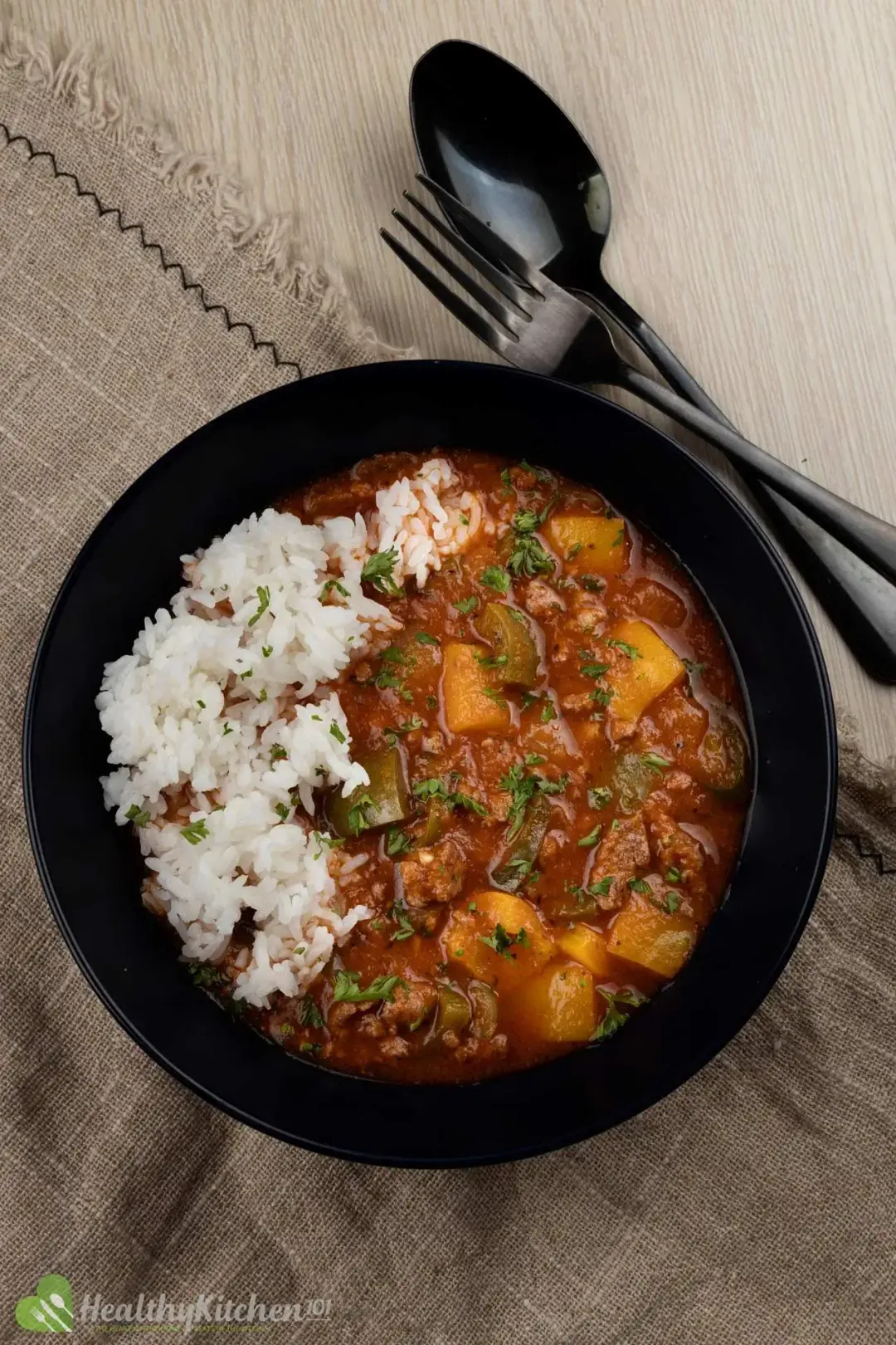 A bowl of cooked rice and soup of pepper and meat poured on the side
