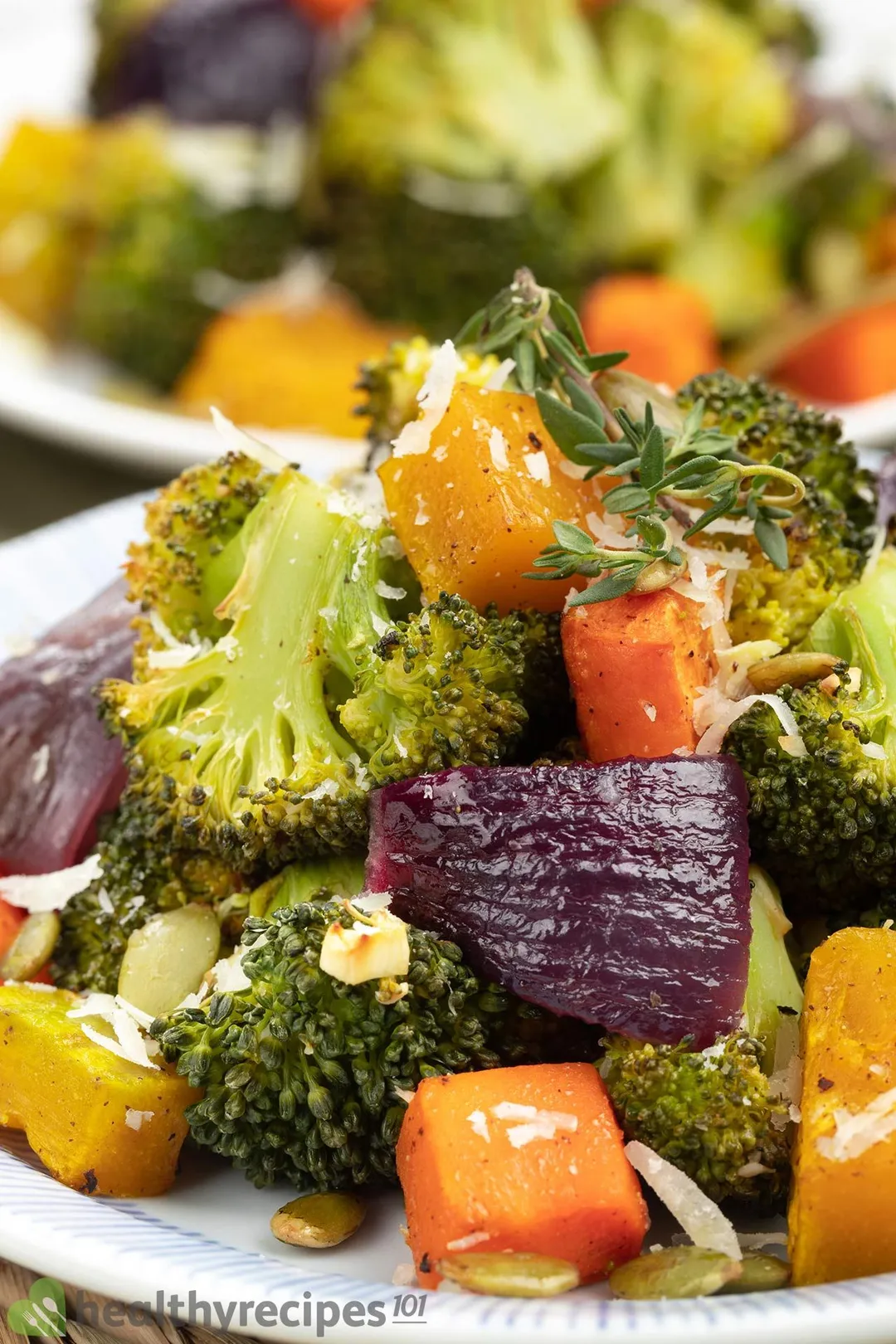 A close-up shot of roasted broccoli florets, squash cubes, and red onion.