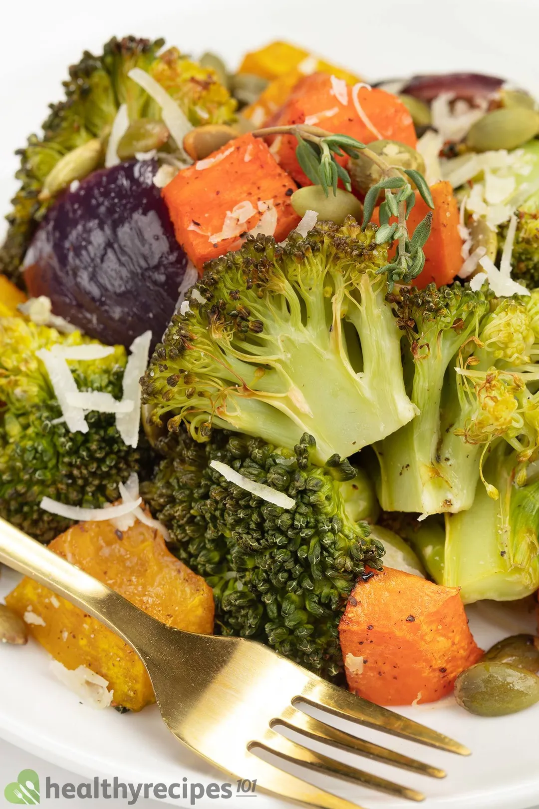 A close-up shot of broccoli florets, squash cubes, shredded cheese, and a fork.