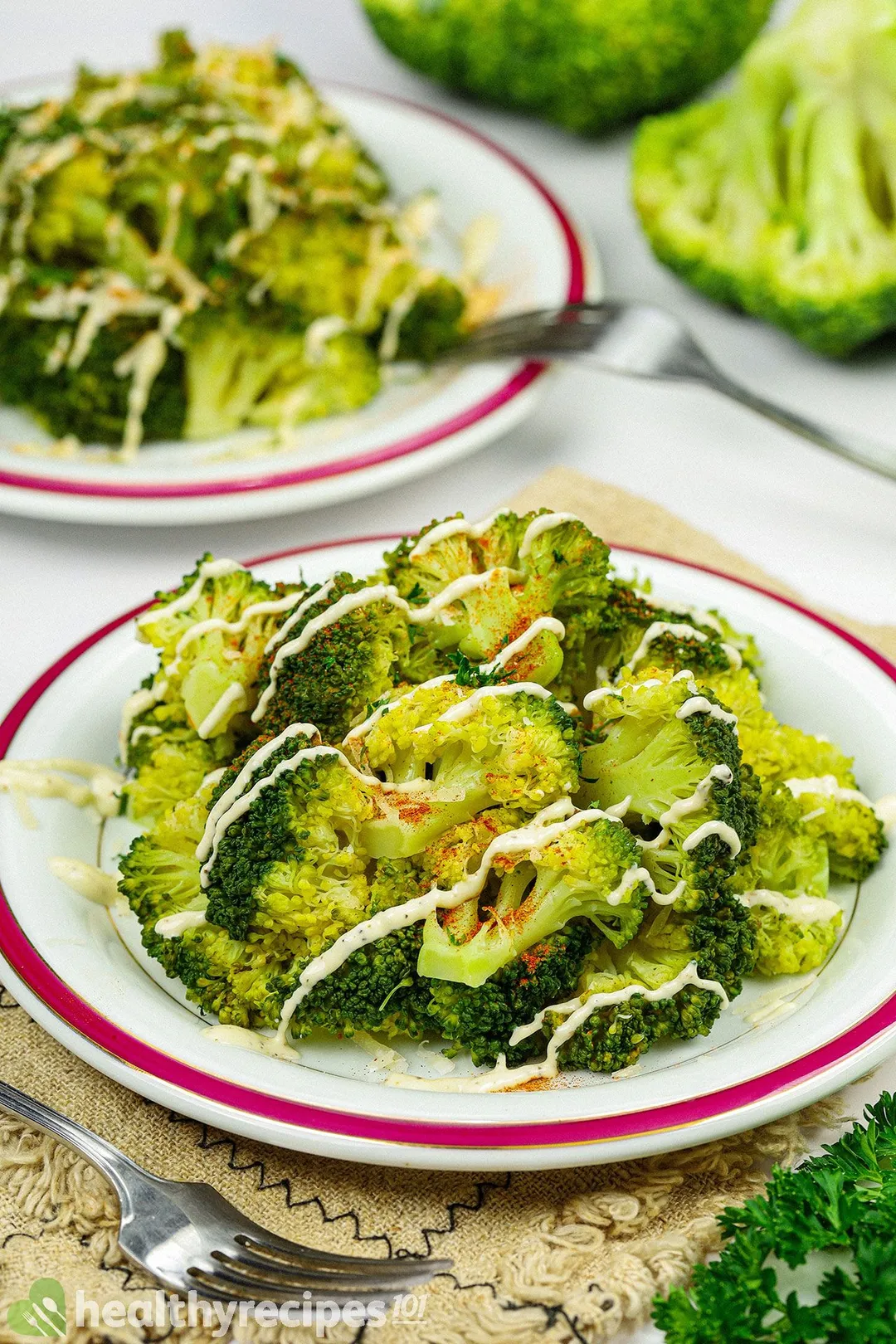 a plate of steamed broccoli with another plate in background