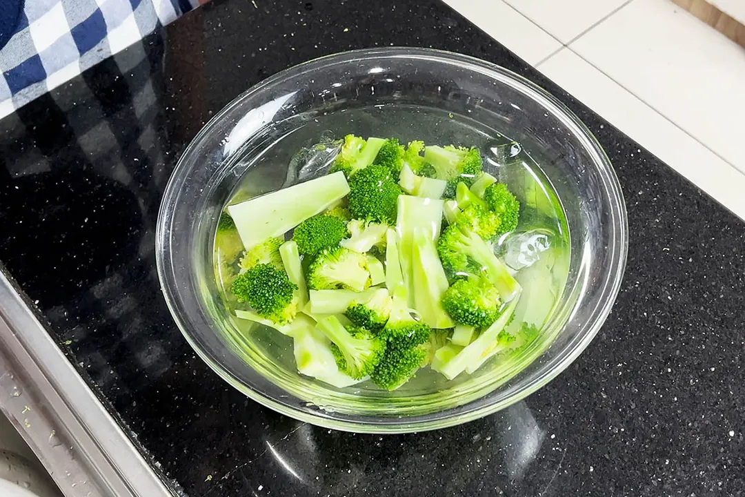 broccoli florets in a glass bowl of ice and water