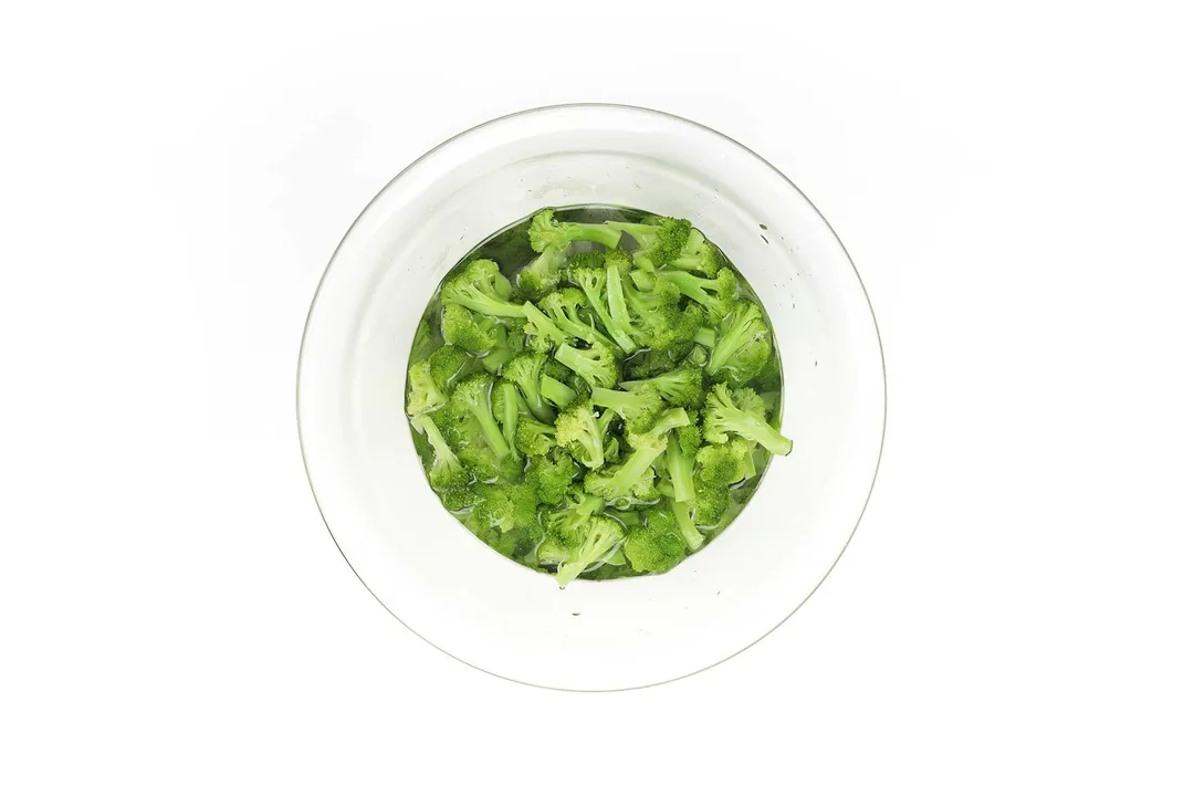 A large glass bowl that contains fresh and bright green broccoli florets