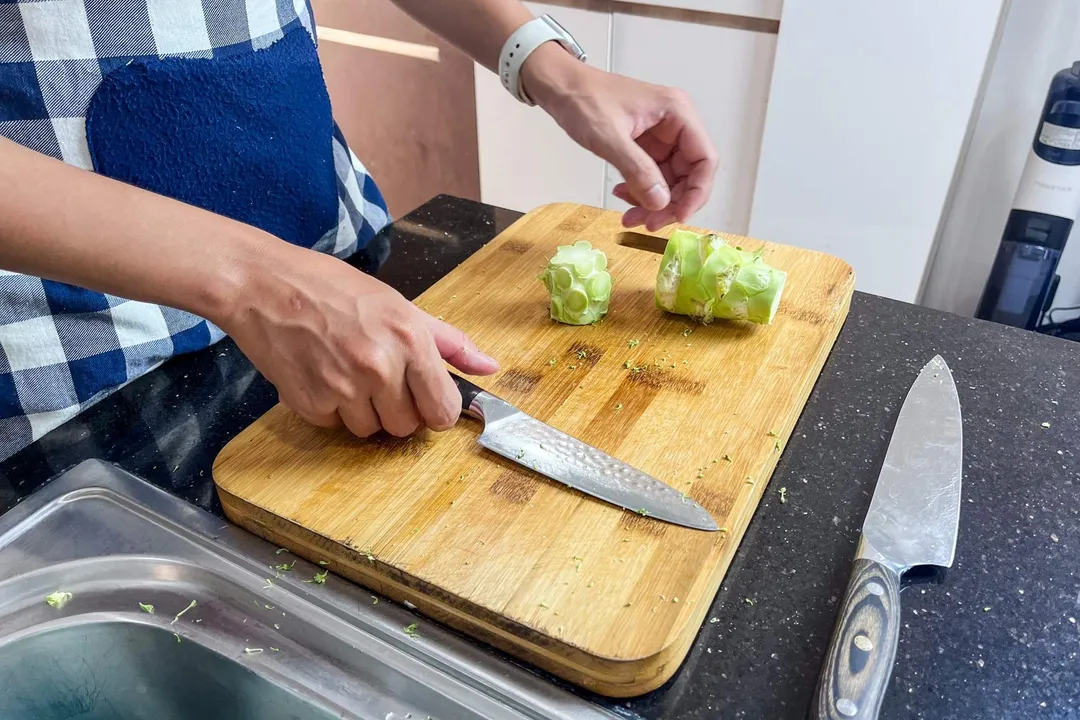 two half of broccoli stalk on a cutting board next to a knife