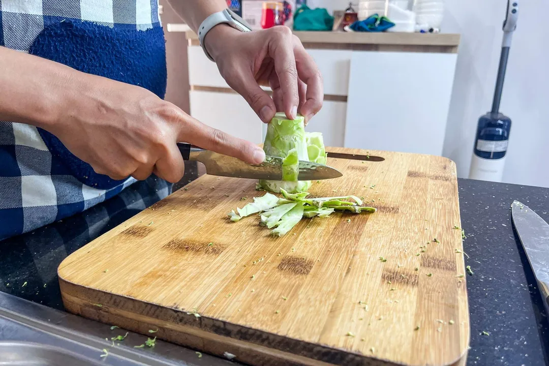 peeling a broccoli stalk on a cutting board