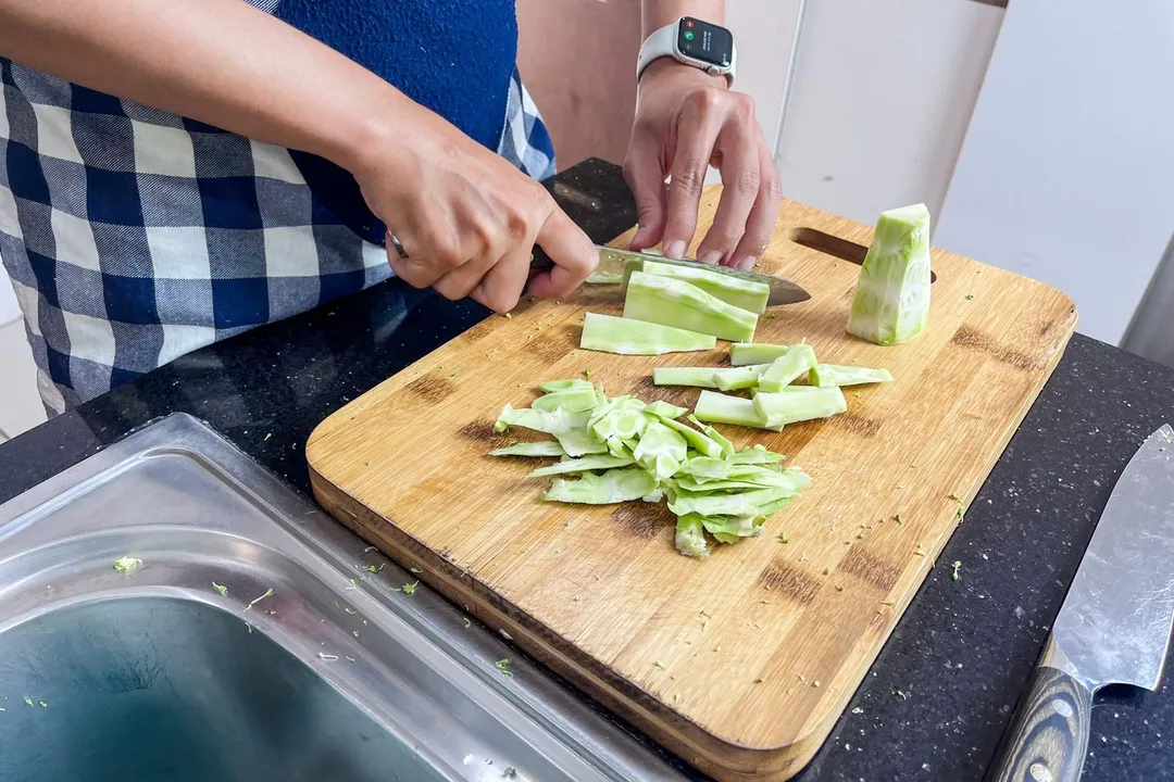 slicing broccoli stalk on a cutting board