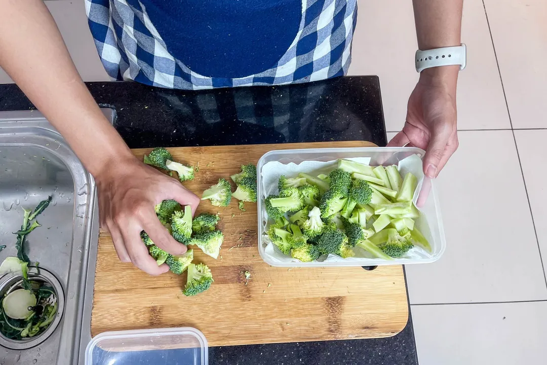 pick broccoli from cutting board into a food container
