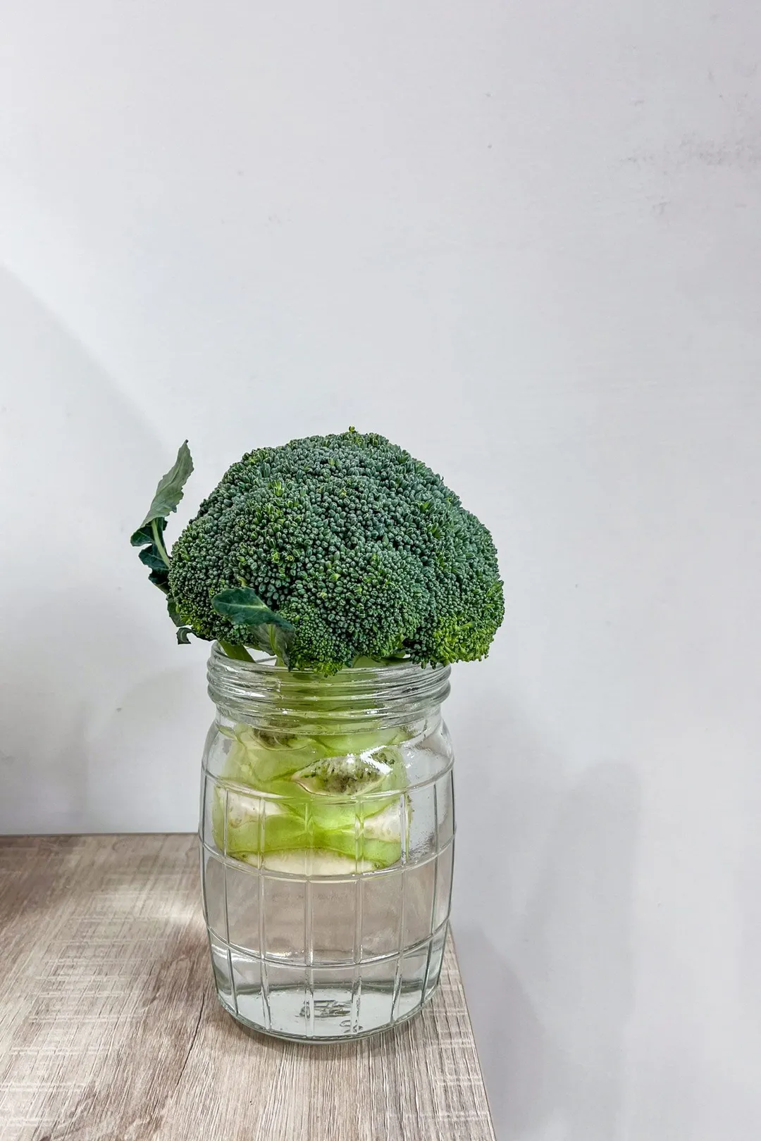a whole broccoli in a glass jar of water