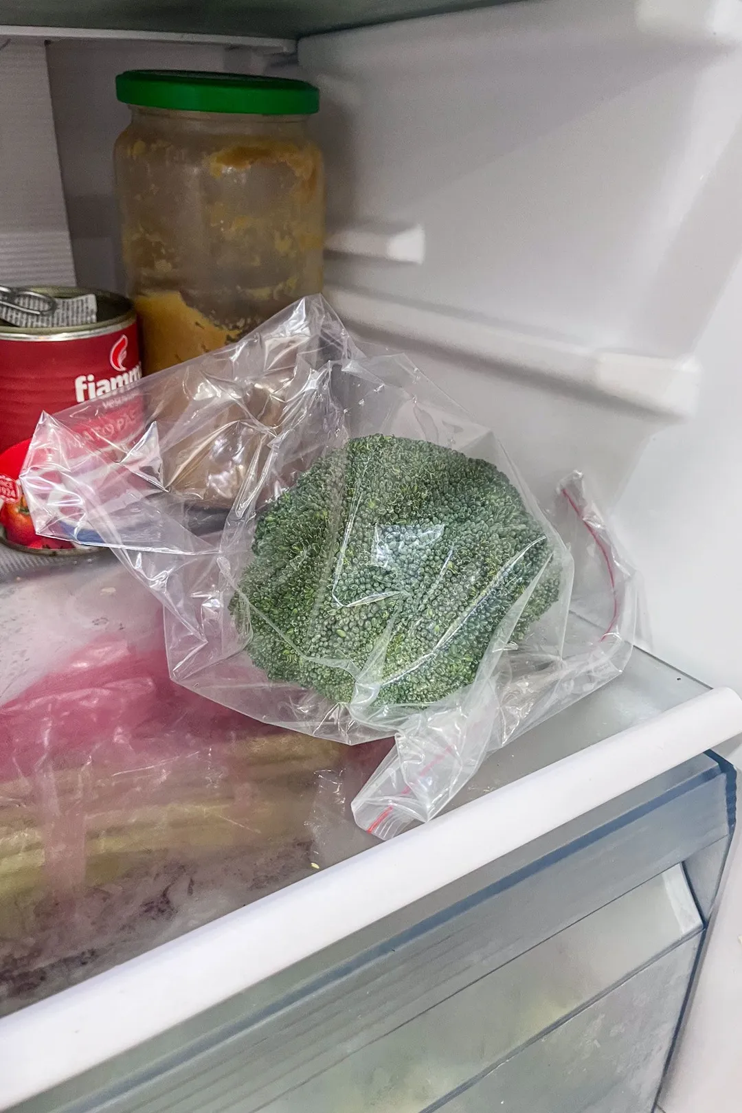 a broccoli in plastic bag in the fridge